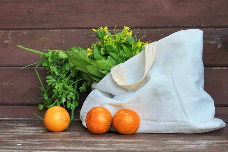 a cotton tote bag with vegetables spilling out of it