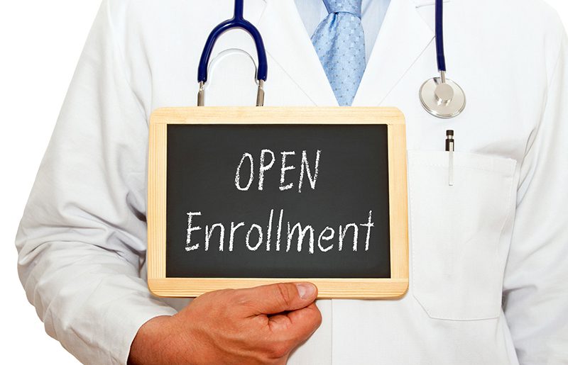 a doctor holding a sign saying open enrollment