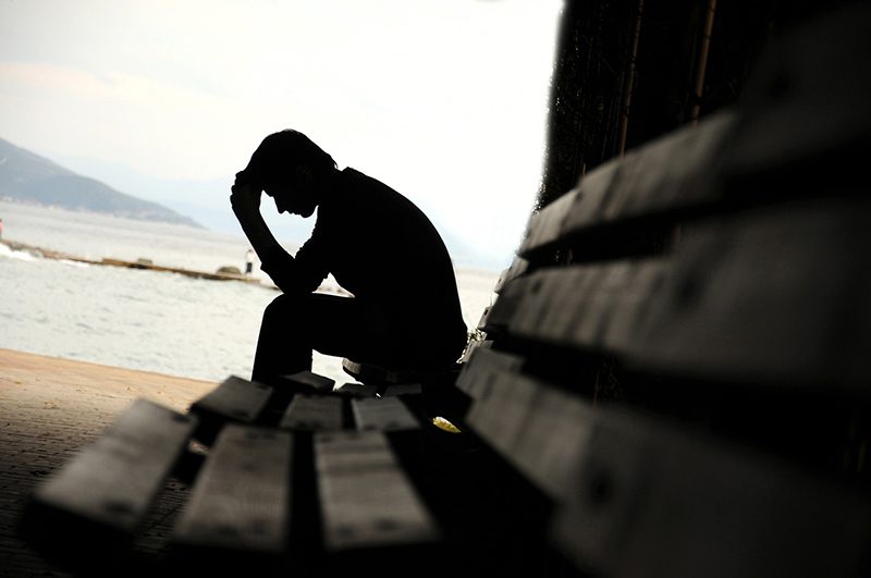 someone who is depressed on a bench